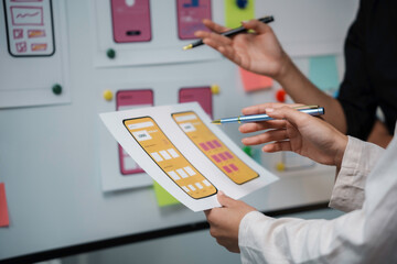 Obraz premium Uiux designers discussing over a new mobile application interface during a meeting