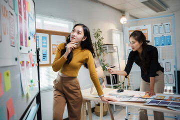 Two uiux designers are discussing over mobile application wireframe design, working together in office