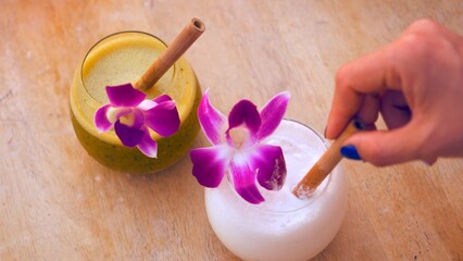 Refreshing tropical cocktails, including pina colada and mojito, decorated with vibrant orchids and bamboo straws. Perfect representation of luxury vacation, relaxation, and exotic summer vibes.