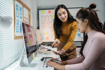 Two uiux designers are discussing over mobile app interface wireframe design at their working desk