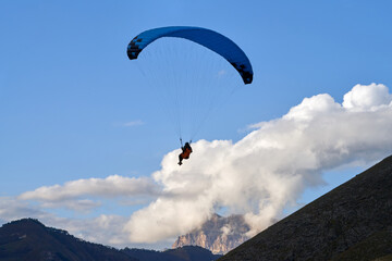 Paraglider soaring in the air on the background of a picturesque cliff in a white cloud. Copy space.