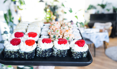 Delivery of sushi and rolls set is hold in hand in the interior modern kitchen of house 