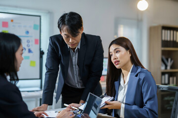 Team of asian businesspeople are having a serious discussion about work, using a laptop and taking notes