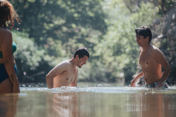 A group of friends having fun in a tranquil outdoor setting, splashing water and enjoying a refreshing summer swim on a sunny day.