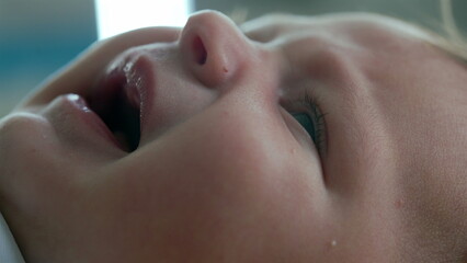 Naklejka premium Macro close-up of a baby’s face in the early stages of crying, with the mouth slightly open as if complaining. focus is on the baby's eye, nose, and soft skin, delicate facial features