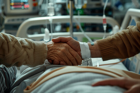 Dos manos estrech&aacute;ndose en una sala de hospital, con pulseras de identificaci&oacute;n m&eacute;dica y equipos intravenosos visibles, simbolizando apoyo y solidaridad