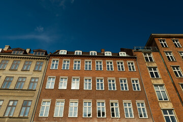 View from below of a brick Scandinavian house in Copenhagen. The house has many large windows. The house is old and historical