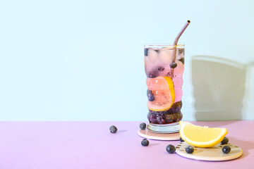 Glass of fresh blueberry lemonade on colorful background