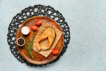 Plate of tasty salmon steak with tomatoes and spices on blue background