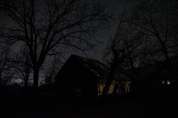 Old house with a Ghost in the forest at misty night or Night scene with House under moon. Old mystic building in dead tree forest.