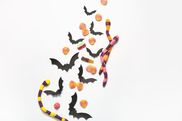 Composition with sweet jelly candies and paper bats on light background