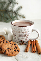 Cup of tasty Christmas cocoa with cookies, marshmallows and cinnamon on white background
