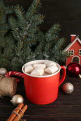 Cup of tasty Christmas cocoa with marshmallows, balls and cinnamon on wooden background