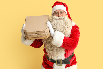 Santa Claus with pizza boxes on yellow background