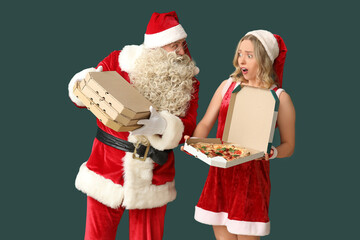 Shocked woman and Santa Claus with boxes of tasty pizza on green background