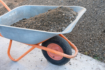 Construction wheelbarrow loaded with sand and gravel mixture for making homemade concrete, close-up