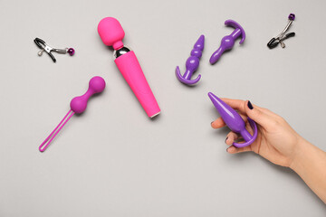 Female hand with different sex toys on light background