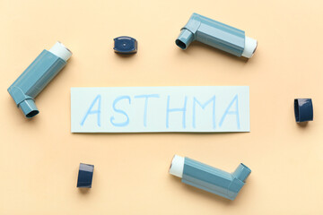Inhalers and paper sheet with text ASTHMA on beige background