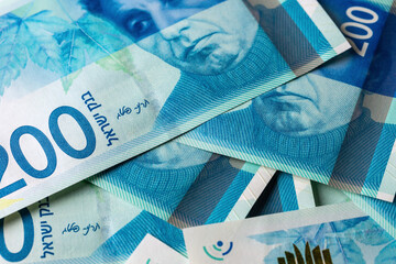 There is a pile of 200 shekel banknotes on the table , a close-up view from above