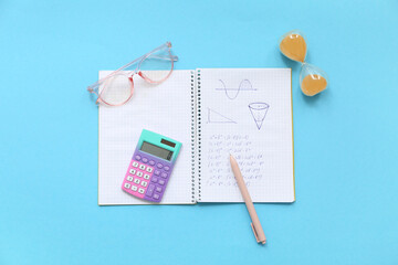 Notebook with eyeglasses, hourglass and school stationery on blue background