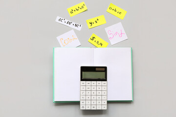 Notebook, calculator, different math formulas and equations on grey background