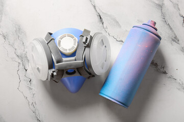Spray paint can and respirator on marble background
