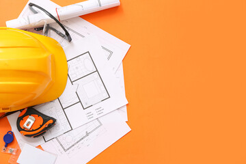 Architect's supplies with hardhat and house plans on orange background