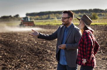 Businessman and farmer woman talking in field