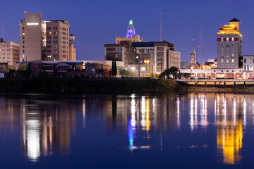 Obraz premium Monroe, Louisiana, USA - April 4, 2024: Evening lights shine on the historic buildings, skyline and river of downtown Monroe.