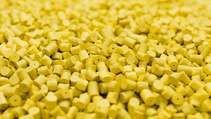 Closeup of yellow plastic polypropylene granules, masterbatch polymer grain with shallow dof. HDPE or PVC resin pellets. 3d render illustration