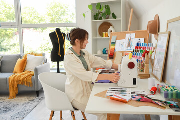 Female fashion designer sewing clothes at table in studio