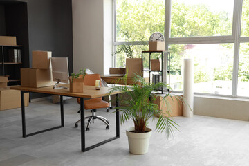 Modern workplace with computer monitor and cardboard boxes in office on moving day