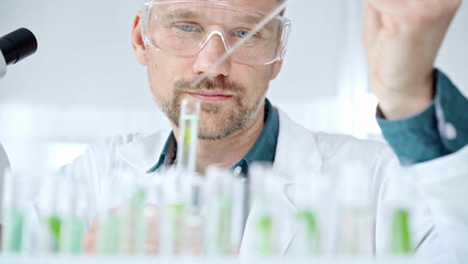 Man with safety glasses is working with lab tubes using a pipette in a modern laboratory, close-up of researcher. Science and medicine