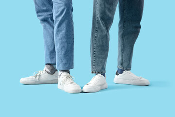 Young men in white sneakers on blue background