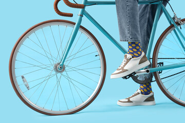 Young man in sneakers with bicycle on blue background