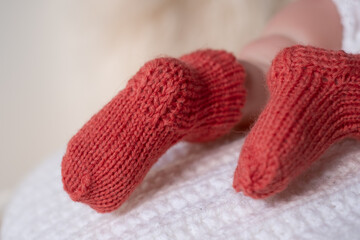 Soft knitted booties on a baby, resting comfortably on a cozy white blanket in a serene indoor environment