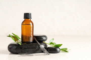 Acupuncture needles, oil and spa stones on light background