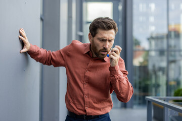 Man wearing smart casual shirt using inhaler for asthma outdoors, representing respiratory difficulty relief. Image conveys health challenges, medication use, and urban lifestyle.