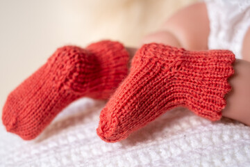 Cute knitted orange baby booties on a soft blanket during a cozy indoor setting