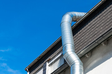 Metal ducting installation on a residential roof against a blue sky