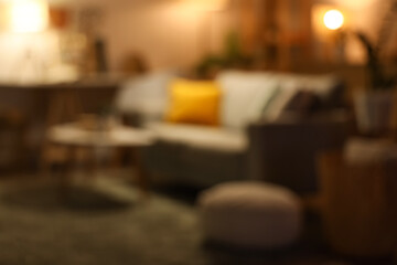 Interior of dark living room with sofa, coffee table and glowing lamps. Blurred view