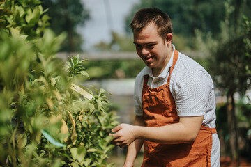 A young gardener with down syndrome happily tending to plants in a sunny garden. He is wearing a...