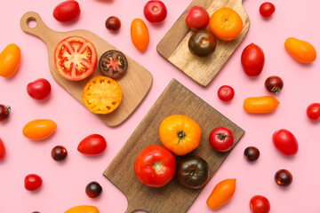 Wooden boards with different fresh tomatoes on pink background