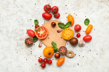 Wooden board with different fresh tomatoes, basil, garlic and peppercorn on white background