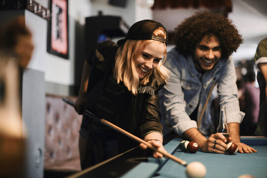 Diverse young friends playing pool and having fun at bar