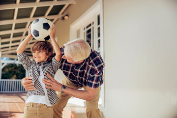 Grandfather and son bonding while playing with a soccer ball on house porch