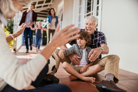 Grandparents and grandchildren playing with soccer ball on house porch - Powered by Adobe