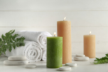 Candles, spa stones and towels on light background