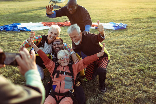 Diverse senior friends taking group photo after skydiving