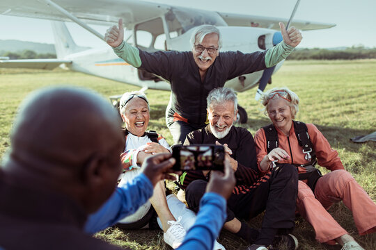 Diverse senior friends taking group photo after skydiving